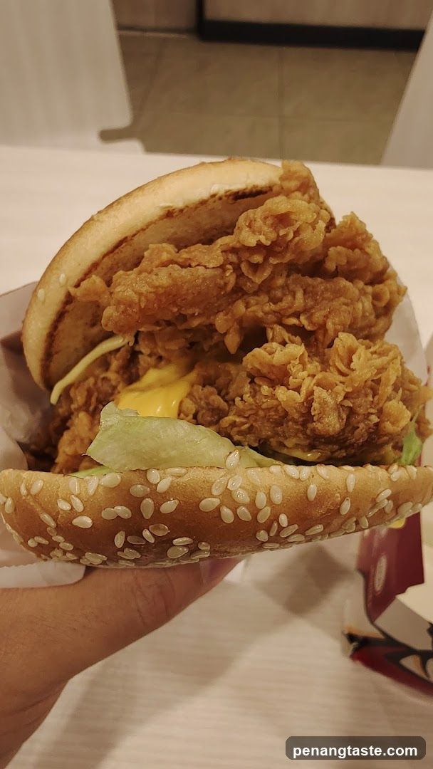 Hand holding fried chicken burger