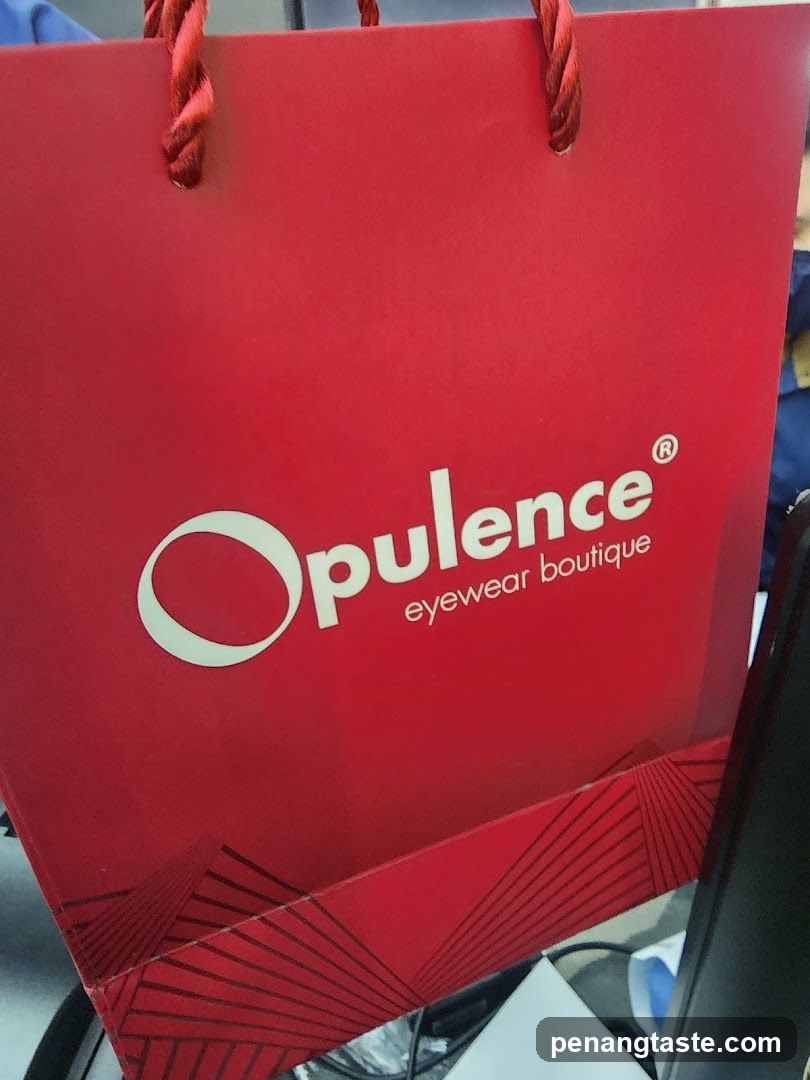 Red shopping bag with "Opulence eyewear boutique" logo