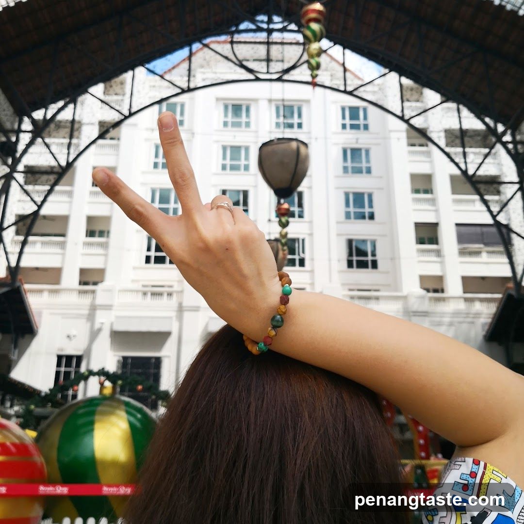 Woman making peace sign with building in background