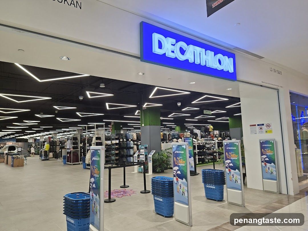 The exterior of a Decathlon store with its prominent blue illuminated sign above the entrance. Inside, shelves are stocked with various sporting goods, including tents, backpacks, and apparel. Blue shopping baskets are stacked near the entrance. Promotional posters for winter sports are displayed.
