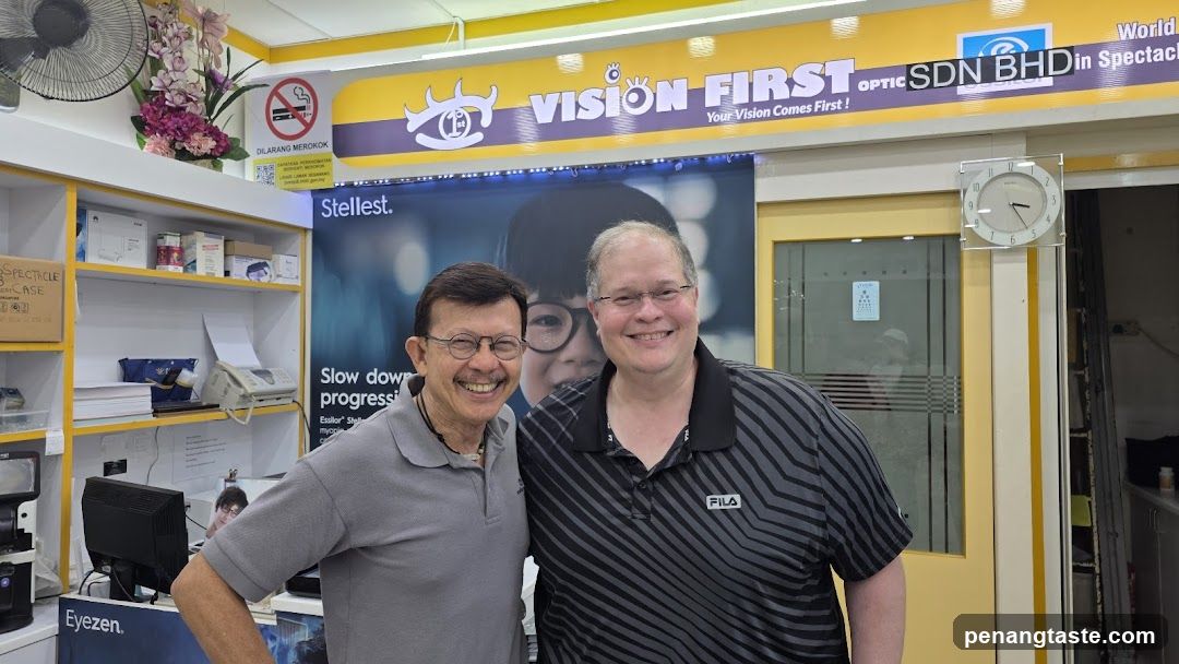 Two men posing inside an optician's store