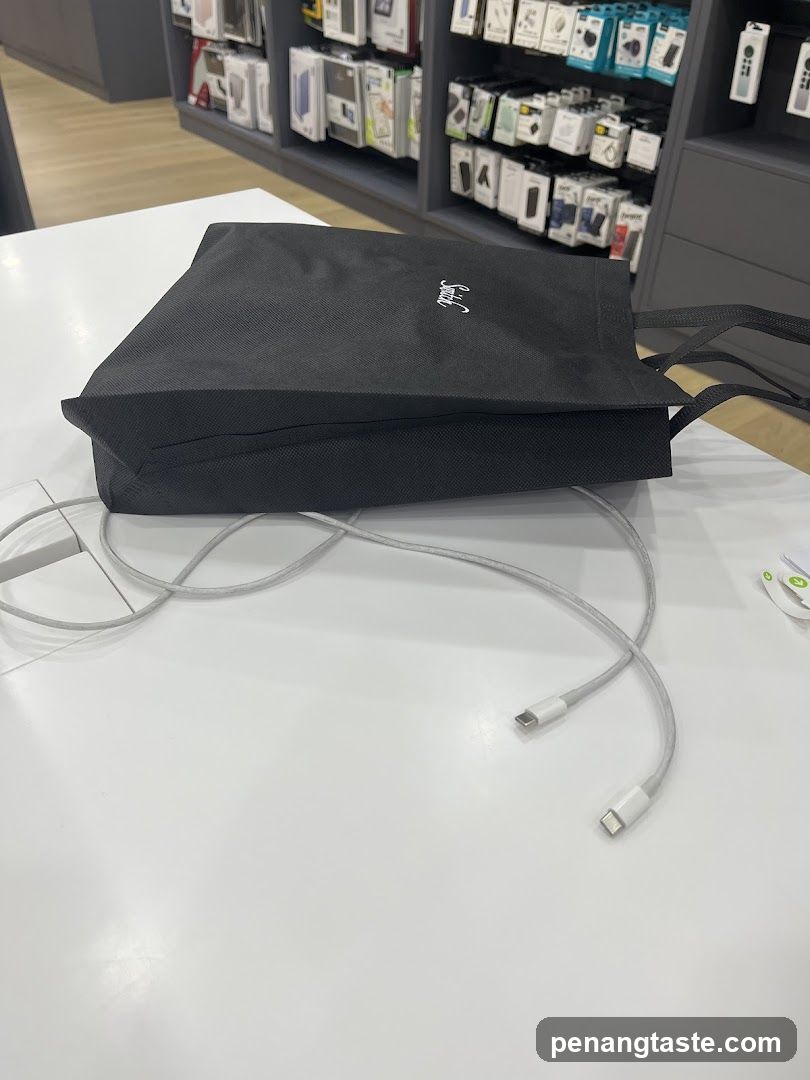 Black tote bag with white logo and charging cables on a white surface