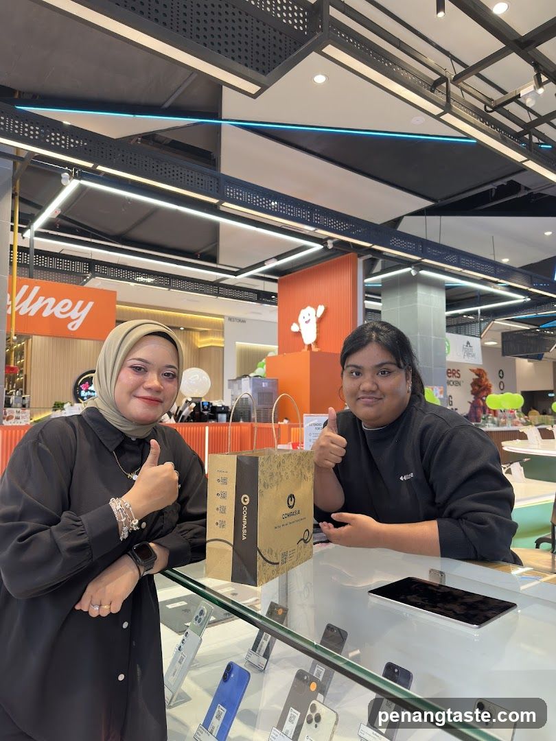 Two individuals posing at a retail counter