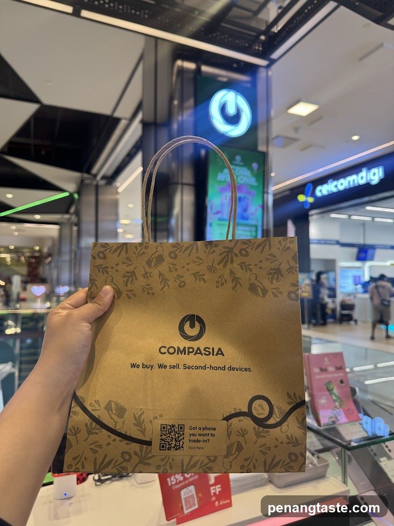 Hand holding COMPASIA shopping bag in mall