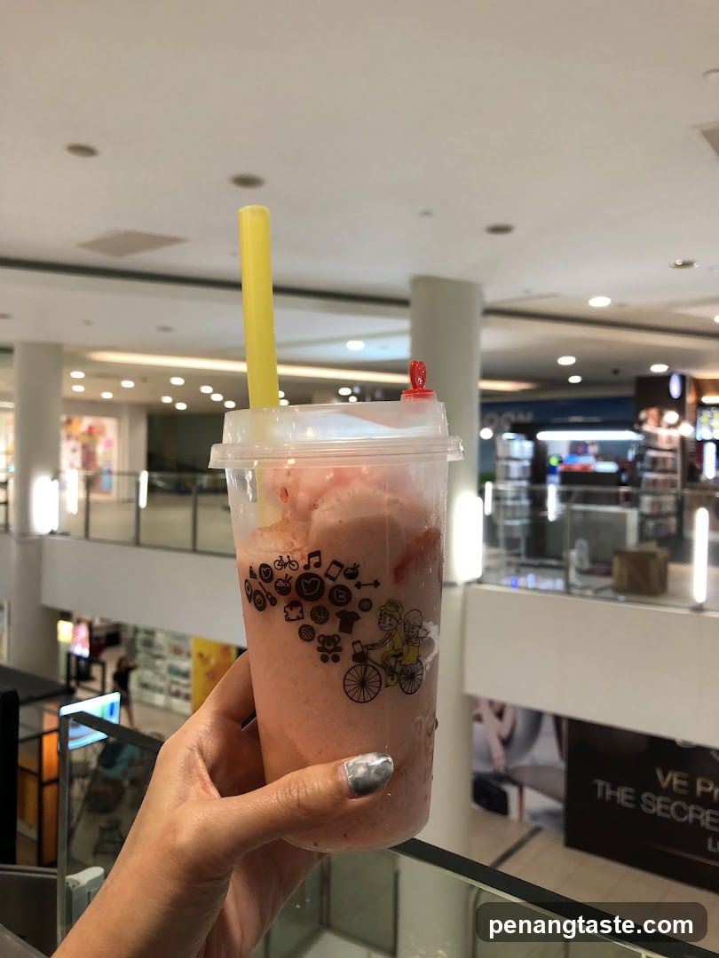 Hand holding a pink beverage in a shopping mall