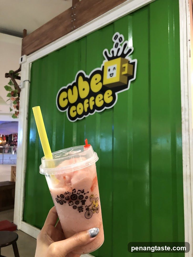Hand holding a pink beverage in front of a green storefront
