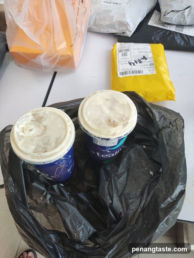 Two beverages in a black trash bag with delivery packages on a table
