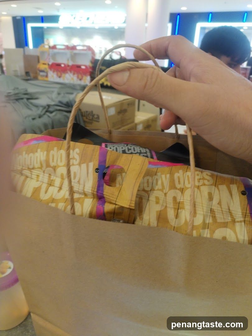 Hand holding popcorn bag in shopping area