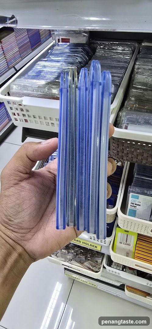 Hand holding blue plastic card holders in store aisle