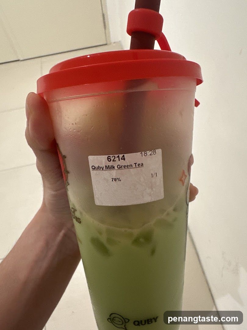 Hand holding Quby Milk Green Tea