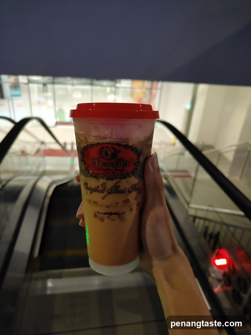 Hand holding Thai tea cup on escalator
