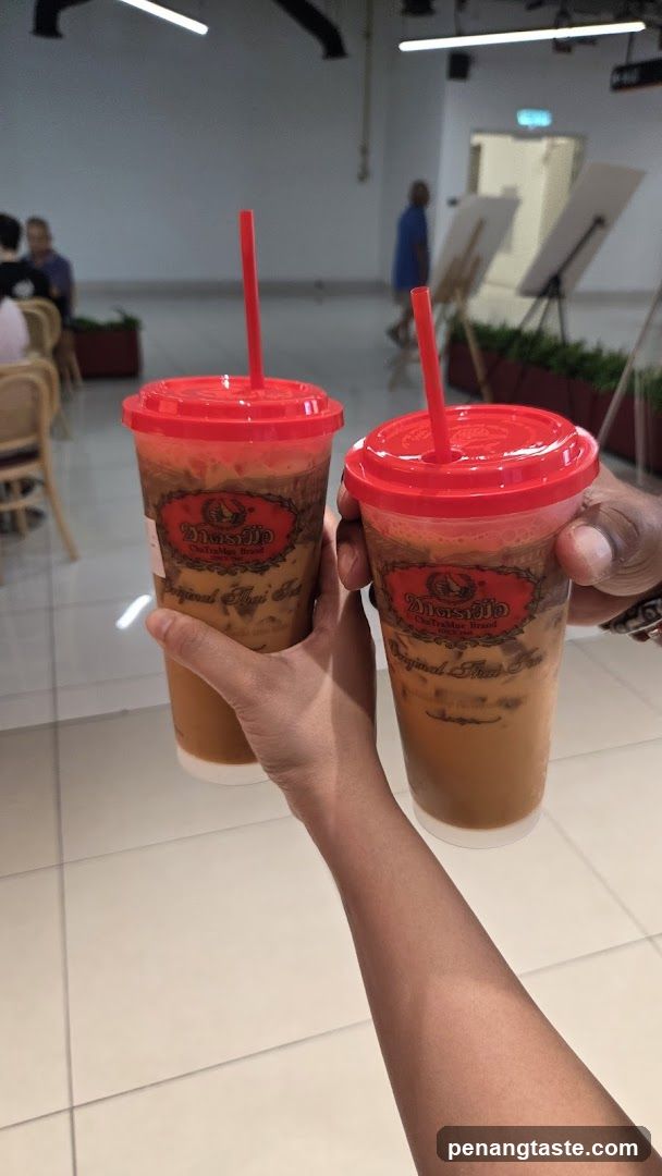 Two Iced Thai Iced Teas Held Up
