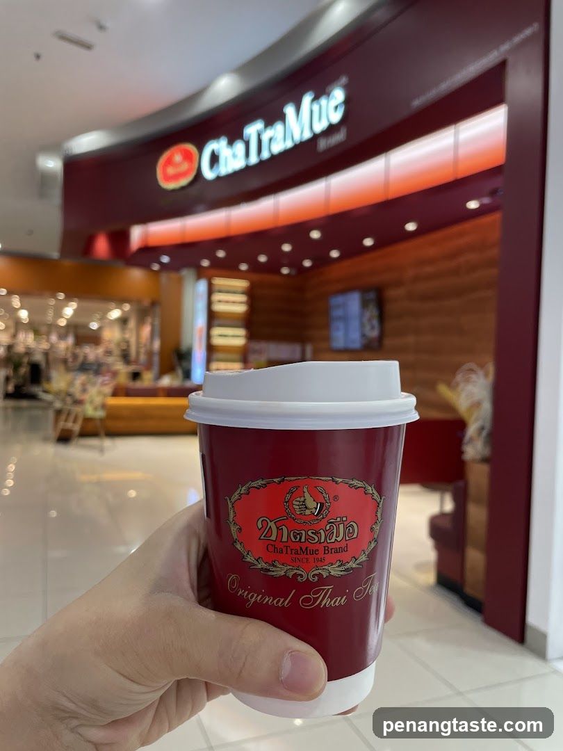Hand holding ChaTraMue tea cup in front of store