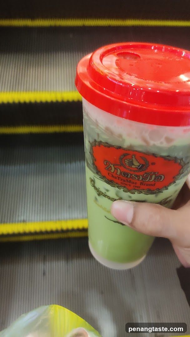 Hand holding ChaTraMue drink on escalator