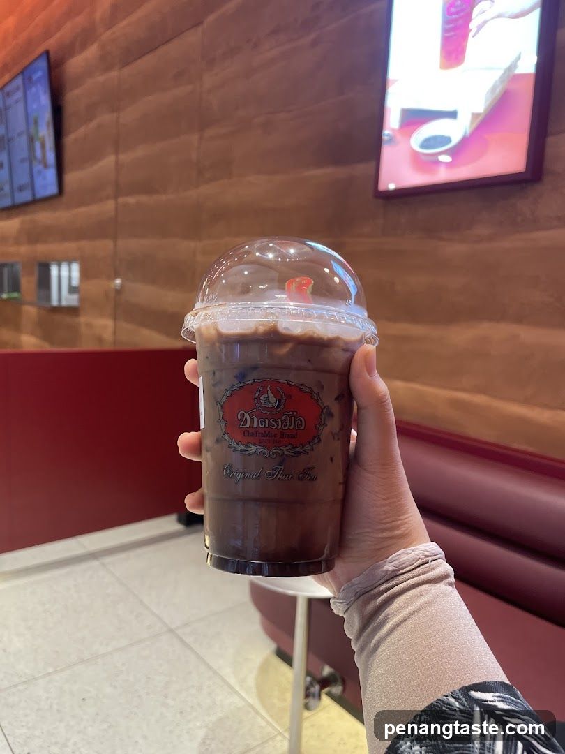 Hand holding Thai tea drink inside a cafe