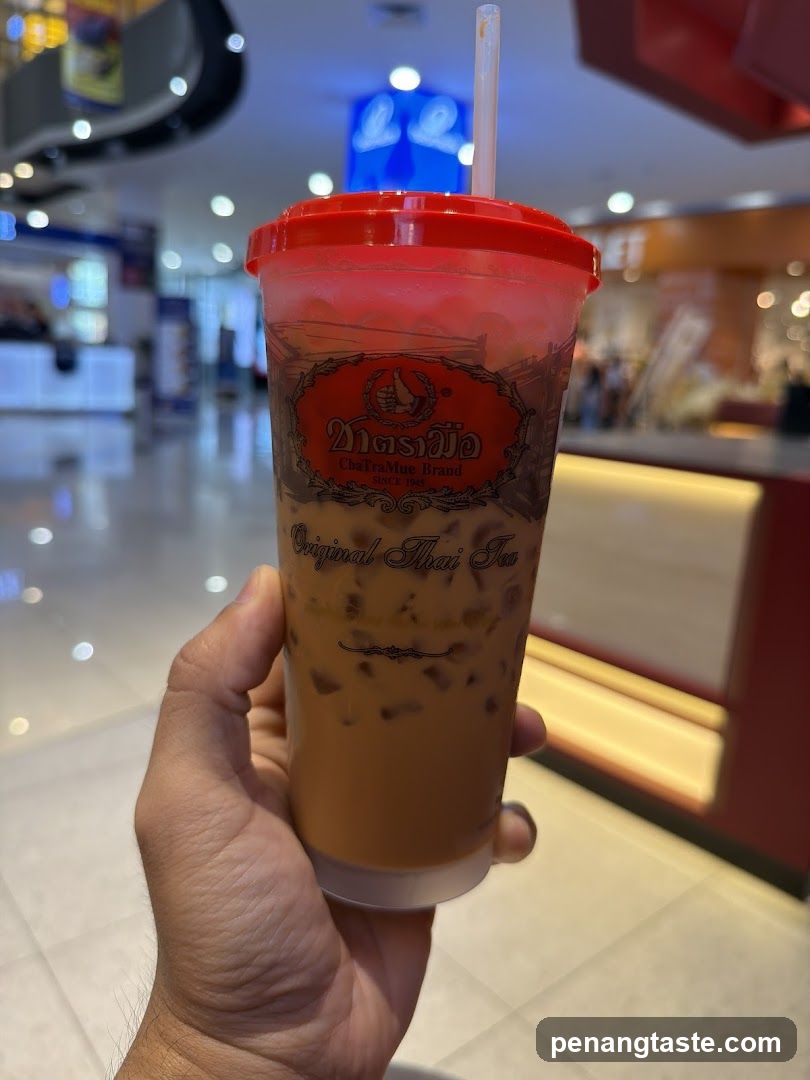 Hand holding Thai iced tea drink