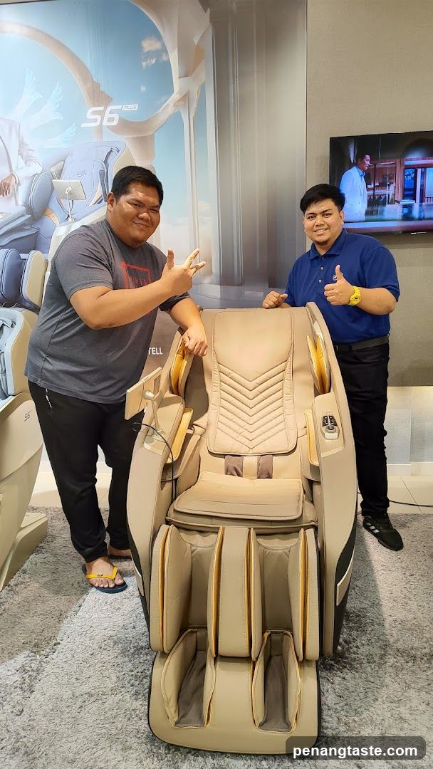 Two men posing with a massage chair in an interior showroom