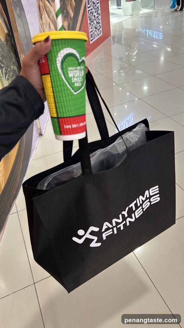 Hand holding branded drink and Anytime Fitness bag