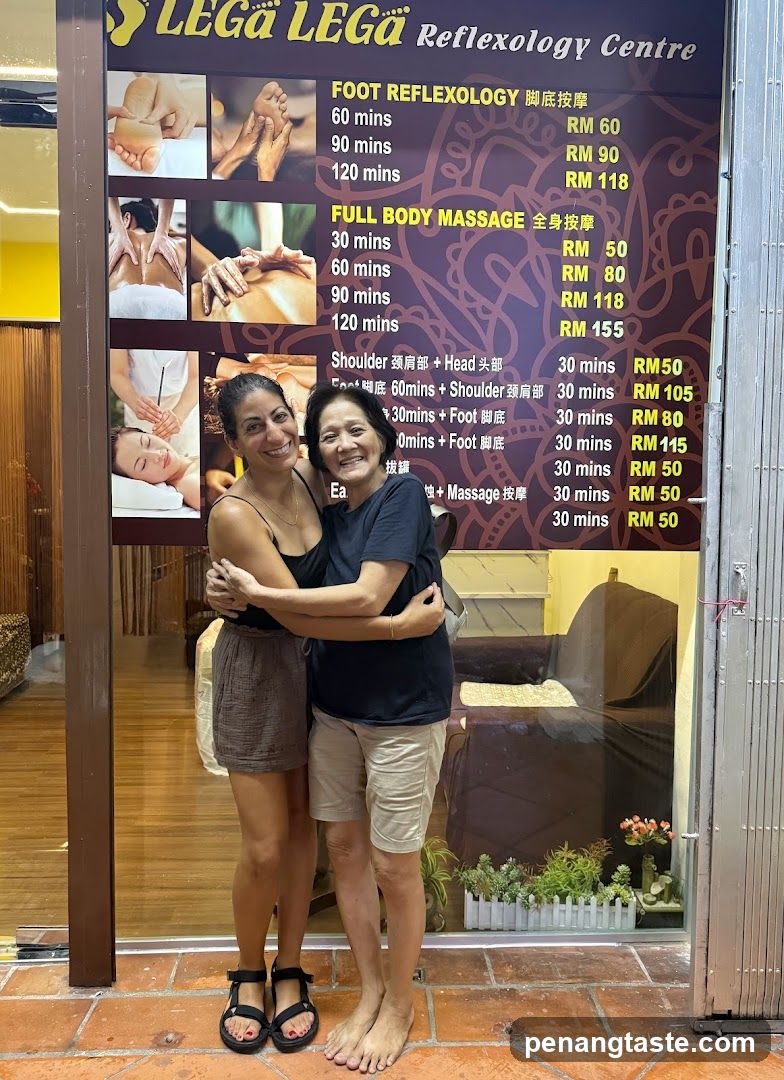 Two women posing in front of a reflexology centre entrance