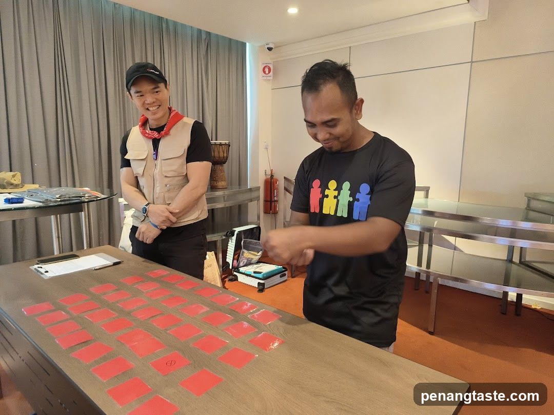 Two men in a room with a table of red cards