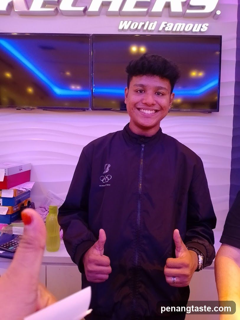Man giving thumbs up in front of Skechers sign