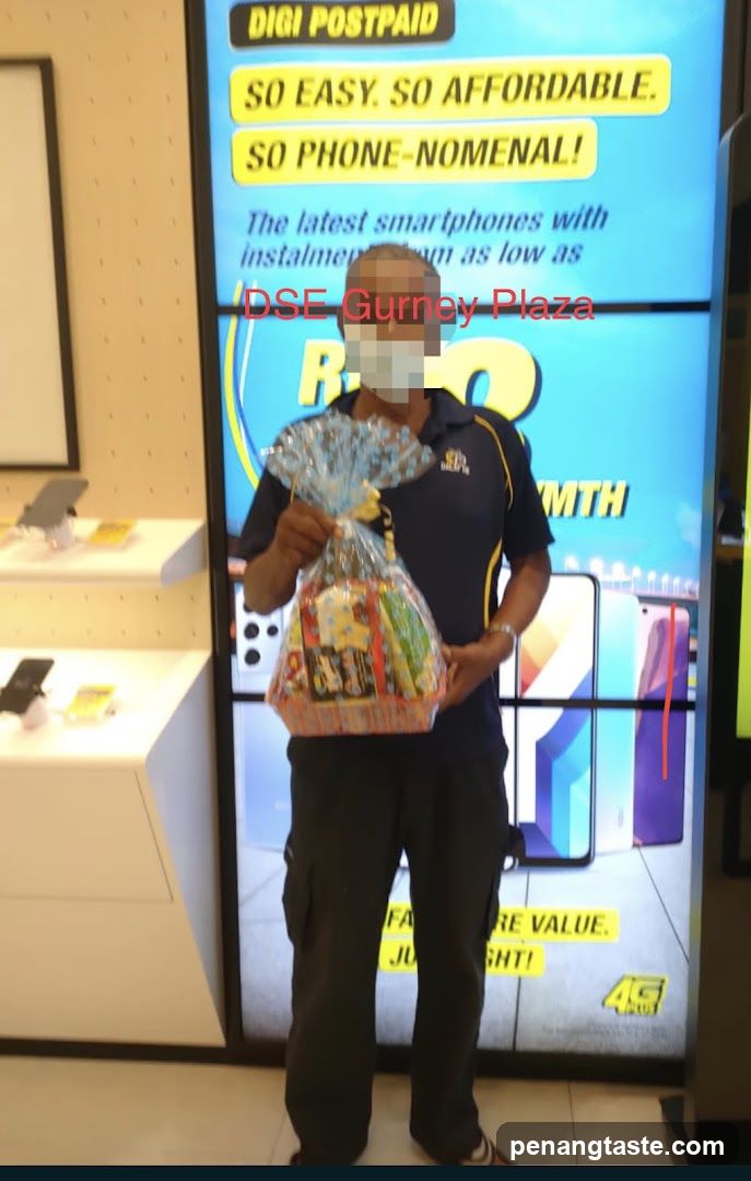 Man holding a gift basket in front of a digital advertisement