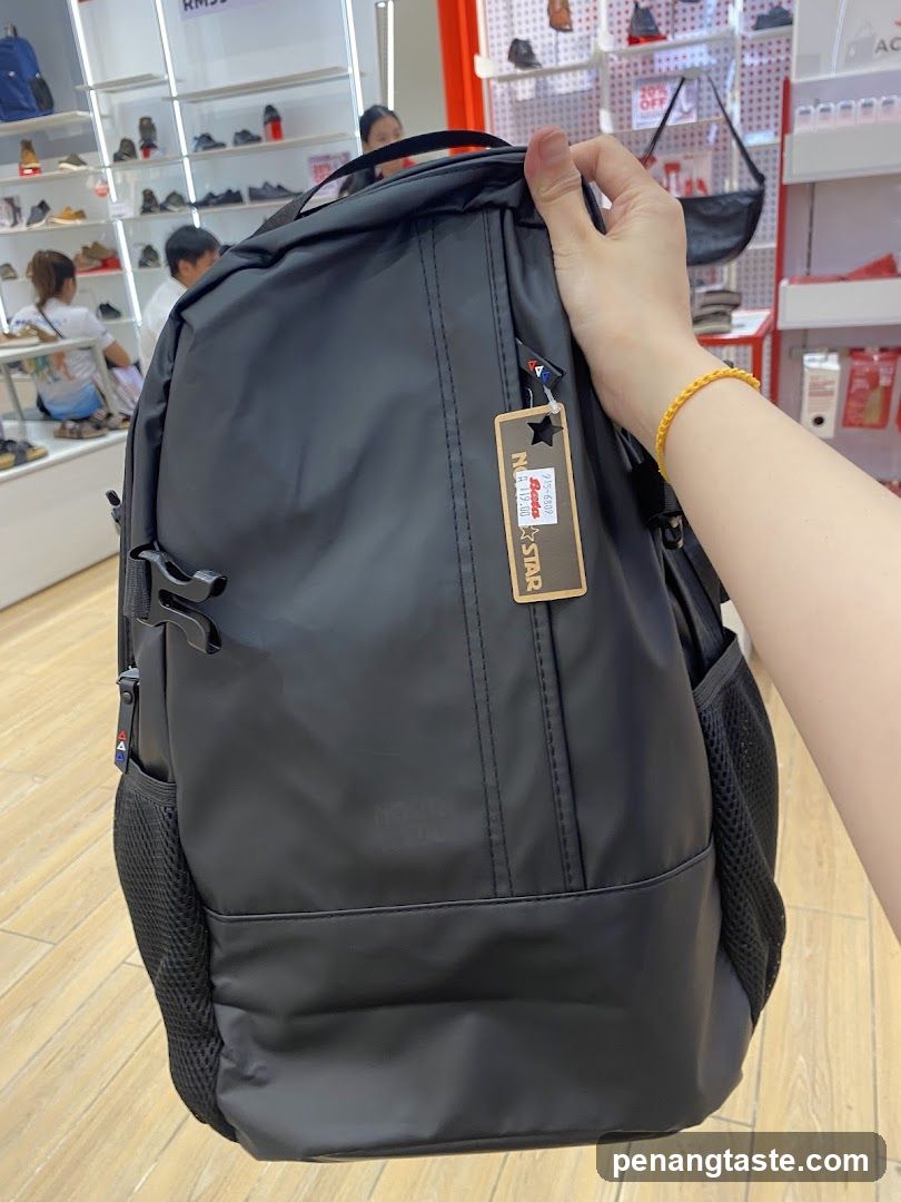 Hand holding black backpack in store
