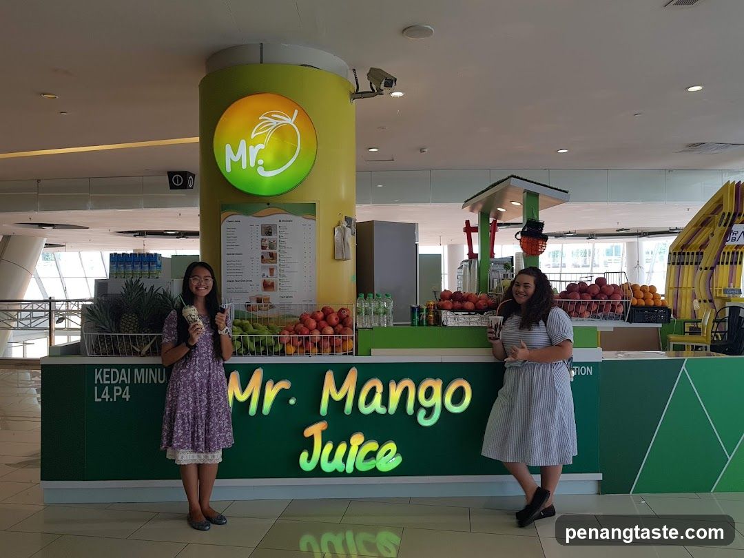 Two women posing in front of a juice stall