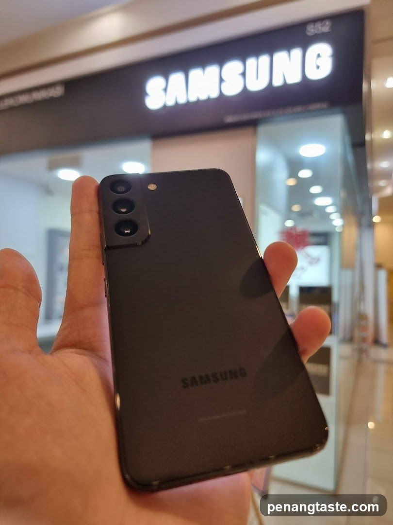 Hand holding Samsung smartphone in front of store