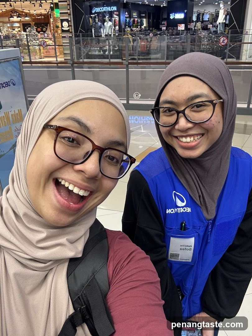 Two women in hijab smiling at camera inside mall