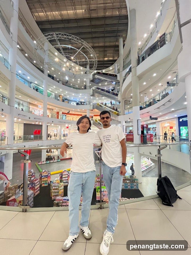 Two individuals posing in a multi-level shopping mall interior