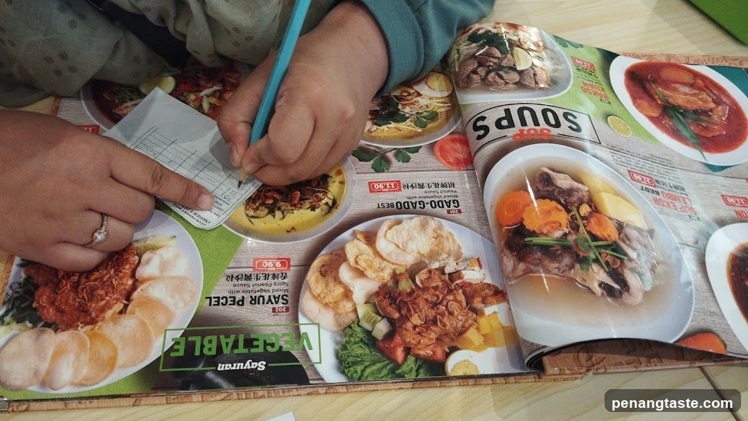 Person writing on paper over open menu