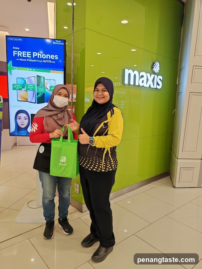 Two individuals posing in front of Maxis store