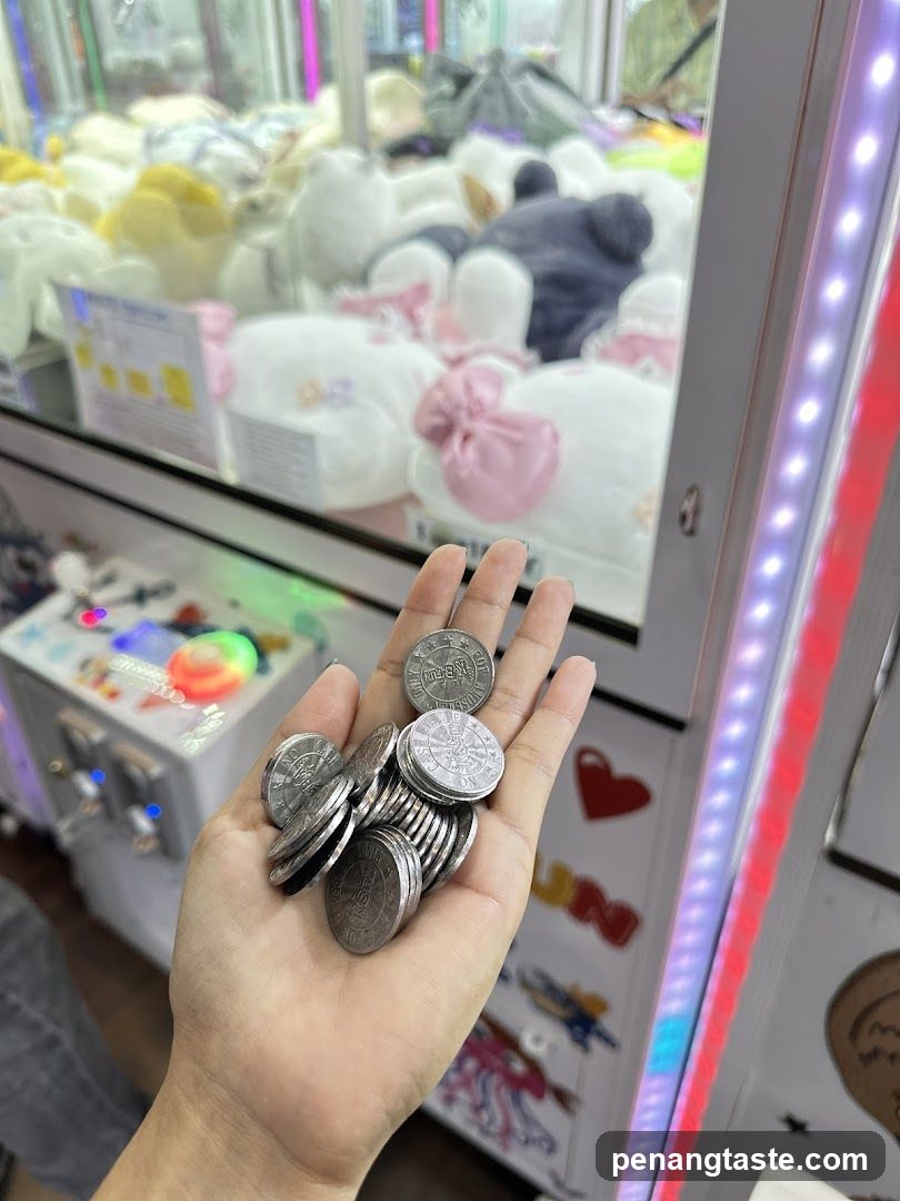 Hand holding coins in front of claw machine