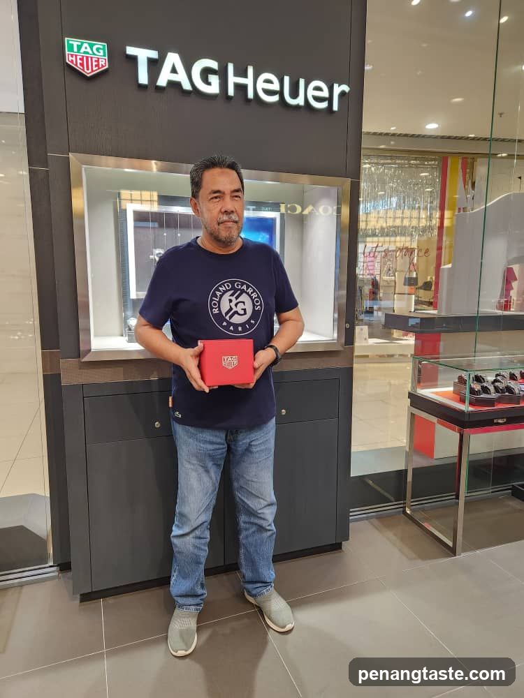 Man holding red watch box in TAG Heuer store
