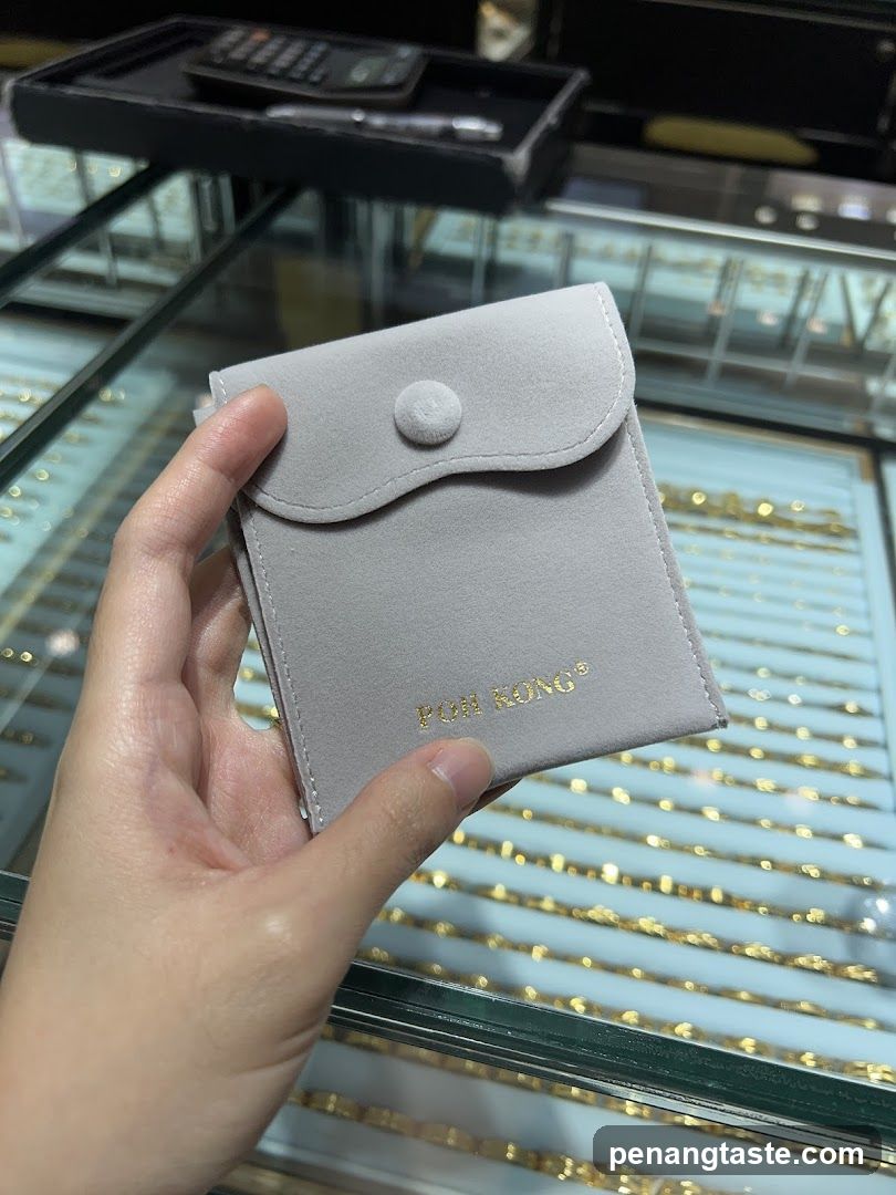Hand holding a gray pouch in jewelry store
