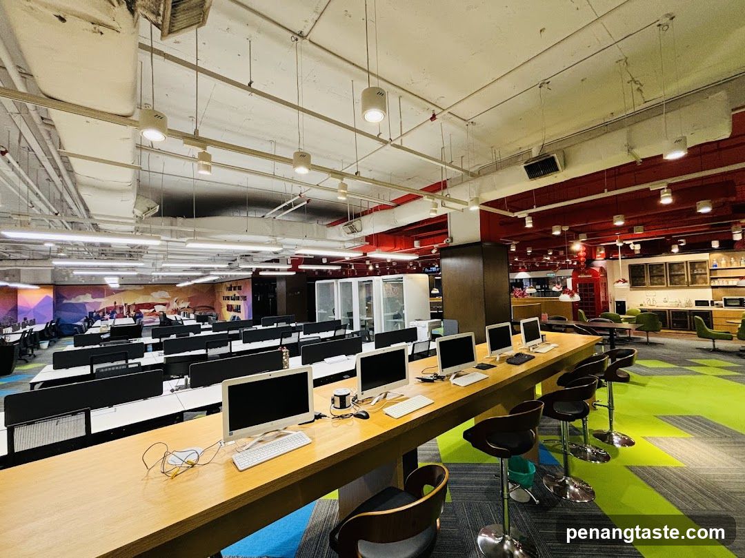 Open-plan office workspace with communal desks and modern lighting fixtures.
