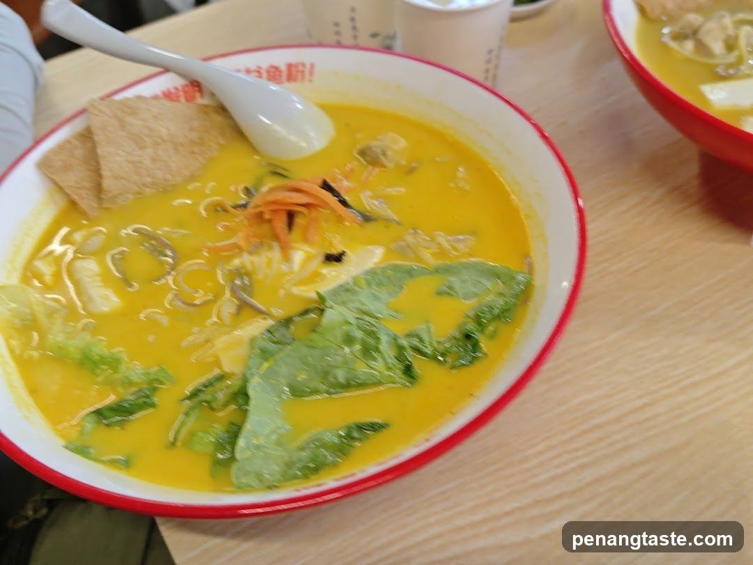 Bowl of yellow soup with noodles and greens