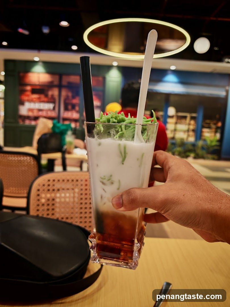 Hand holding a layered drink with green garnish