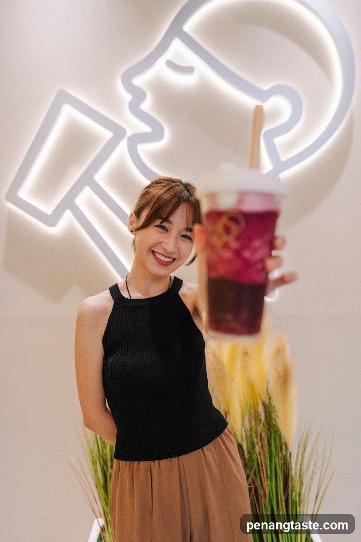 Woman holding a drink in front of neon sign