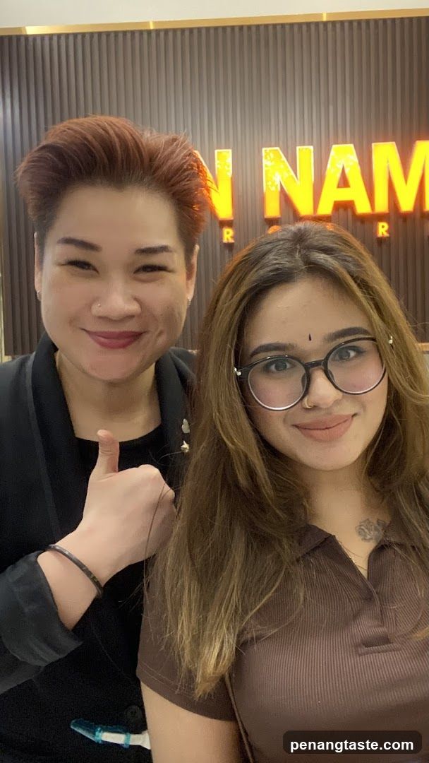 Two women posing in front of a lit sign