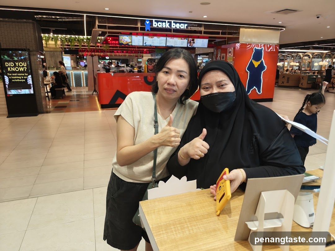 Two women giving thumbs up in a mall food court
