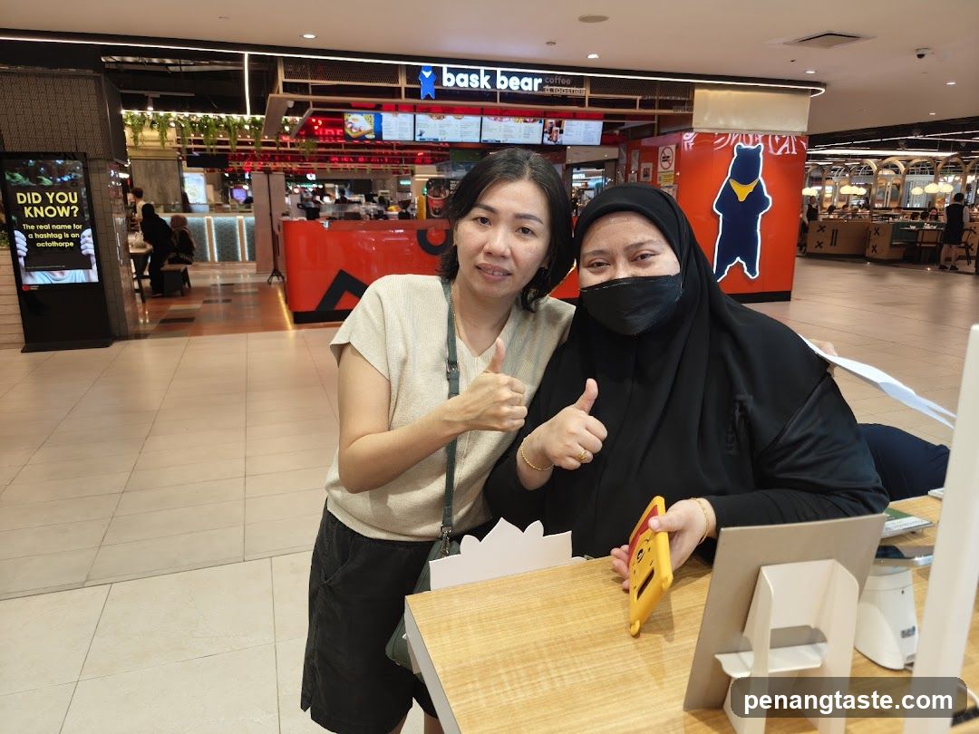 Two women giving thumbs up at a food court
