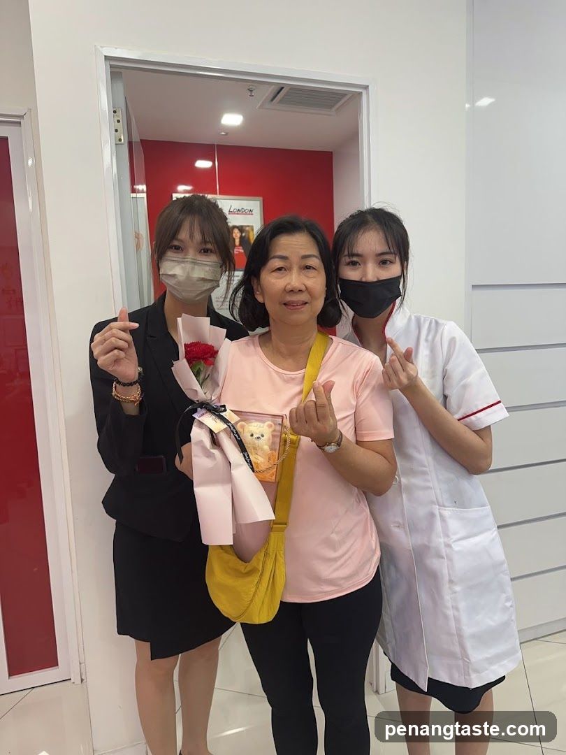Three women posing indoors with flowers and teddy bear gift