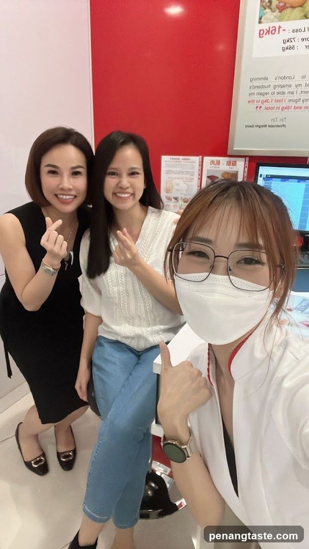 Three women posing indoors near a red wall with posters