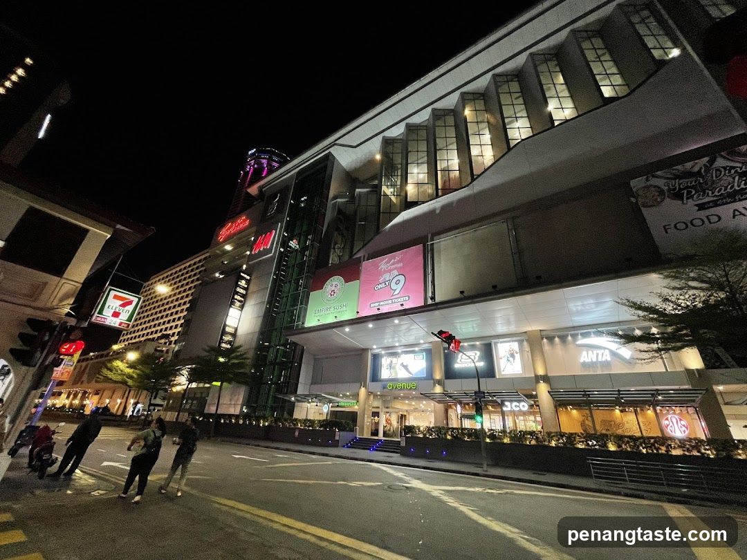 Night street scene with illuminated storefronts and pedestrians