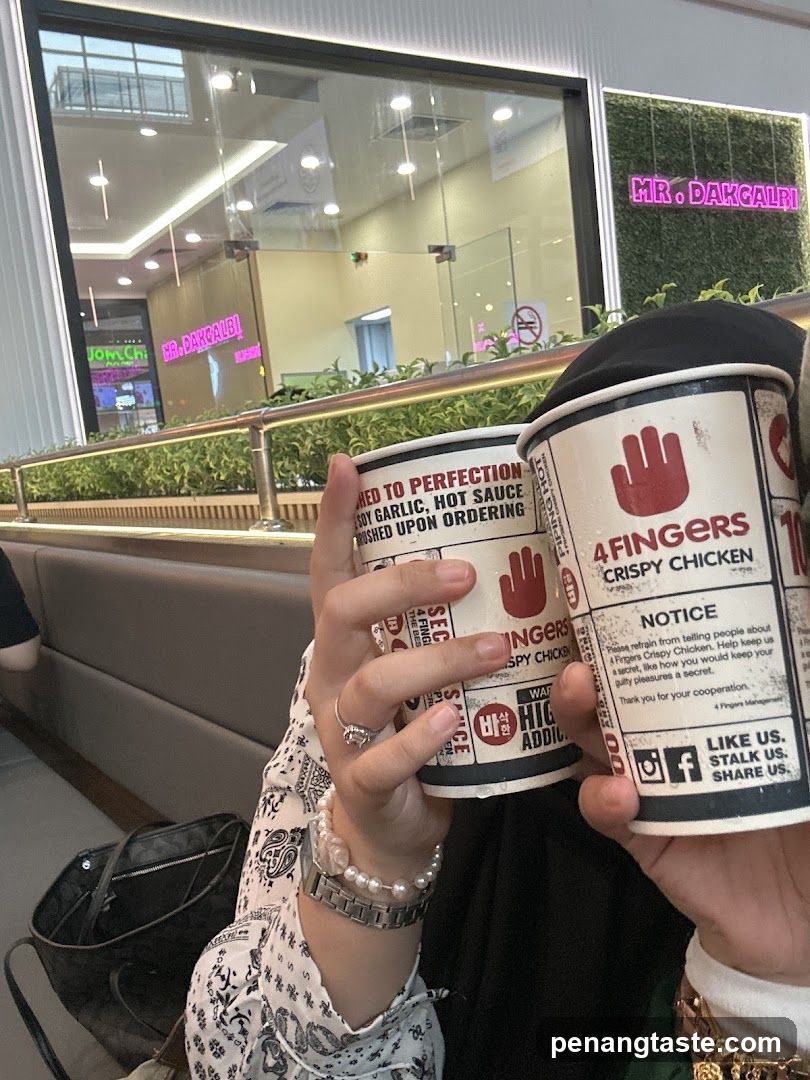 4 Fingers Crispy Chicken cups held up