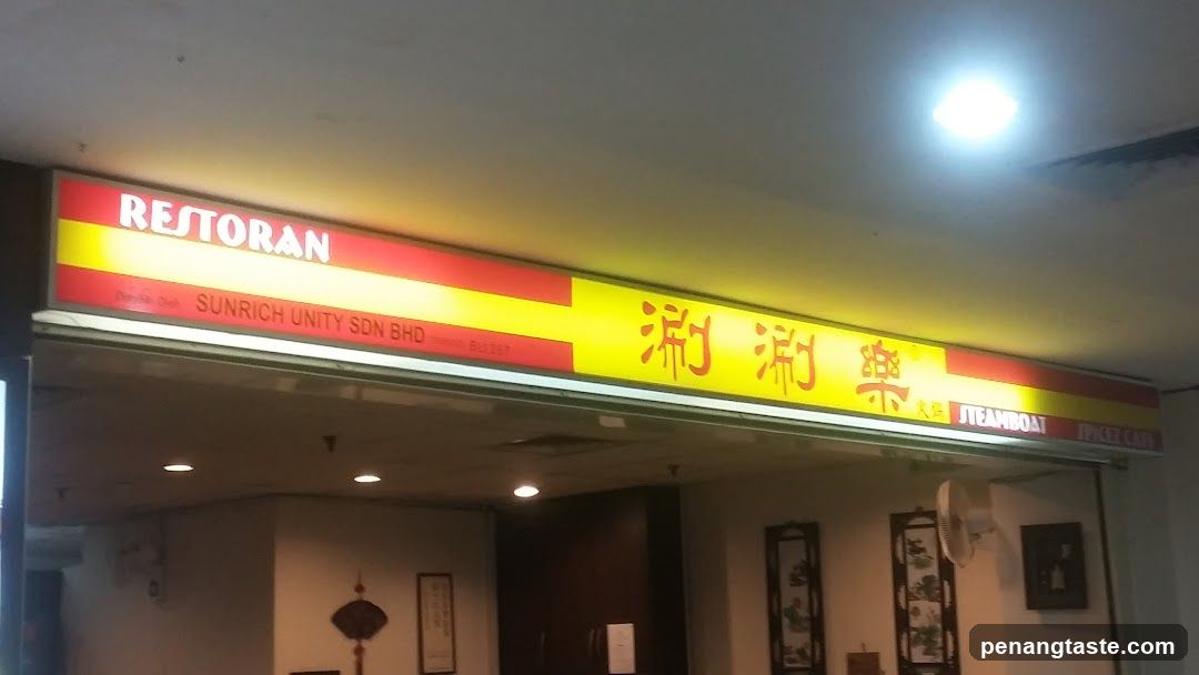 A brightly lit storefront with a yellow and red signboard displaying 'RESTORAN' in English and Chinese characters, along with the company name 'SUNRICH UNITY SDN BHD'. The entrance is visible below the sign.