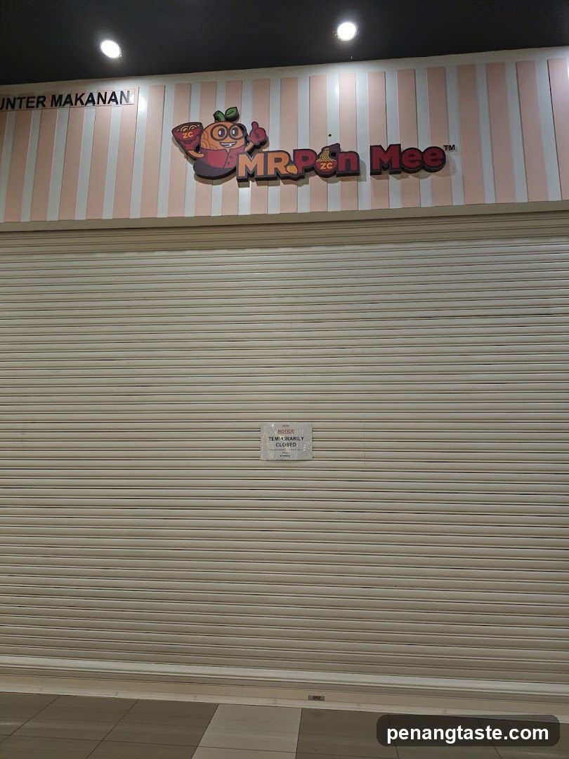 A closed storefront with a striped pink and white facade featuring the 'MR Pon Mee' logo above a metal roller shutter. A small sign is affixed to the center of the shutter.