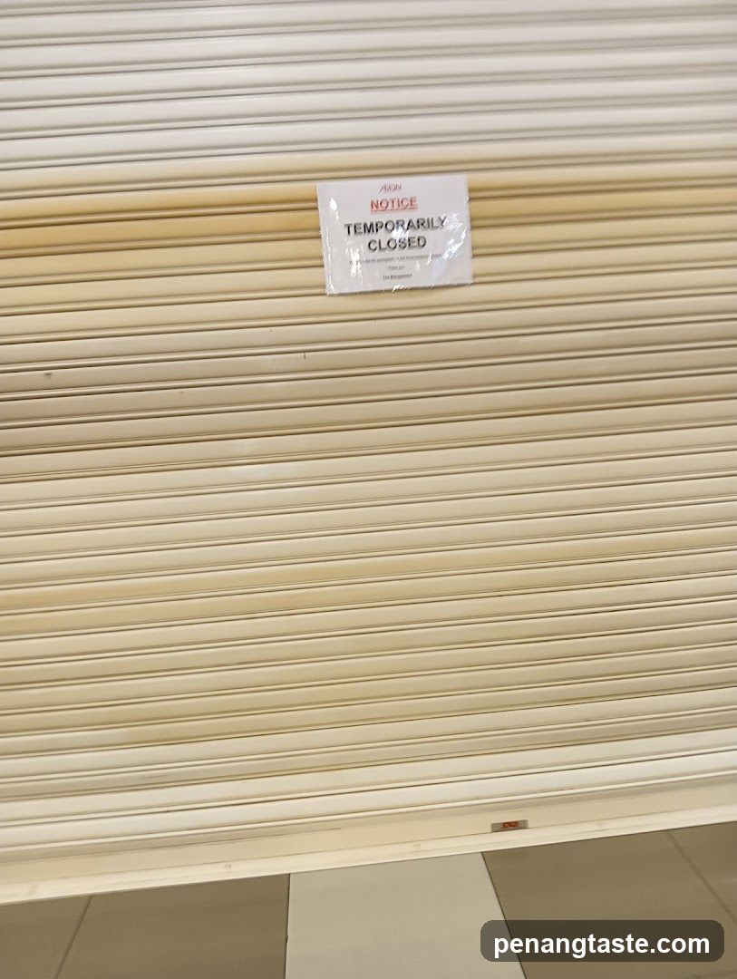 A closed beige metal roller shutter with a white notice sign attached near the top center. The sign reads 'NOTICE TEMPORARILY CLOSED' in bold black and red text, indicating temporary closure of the storefront.
